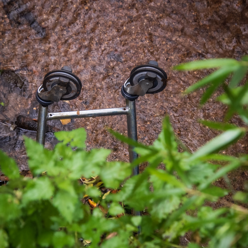 Two grasping legs of a shopping trolley upturned in a shallow creek.